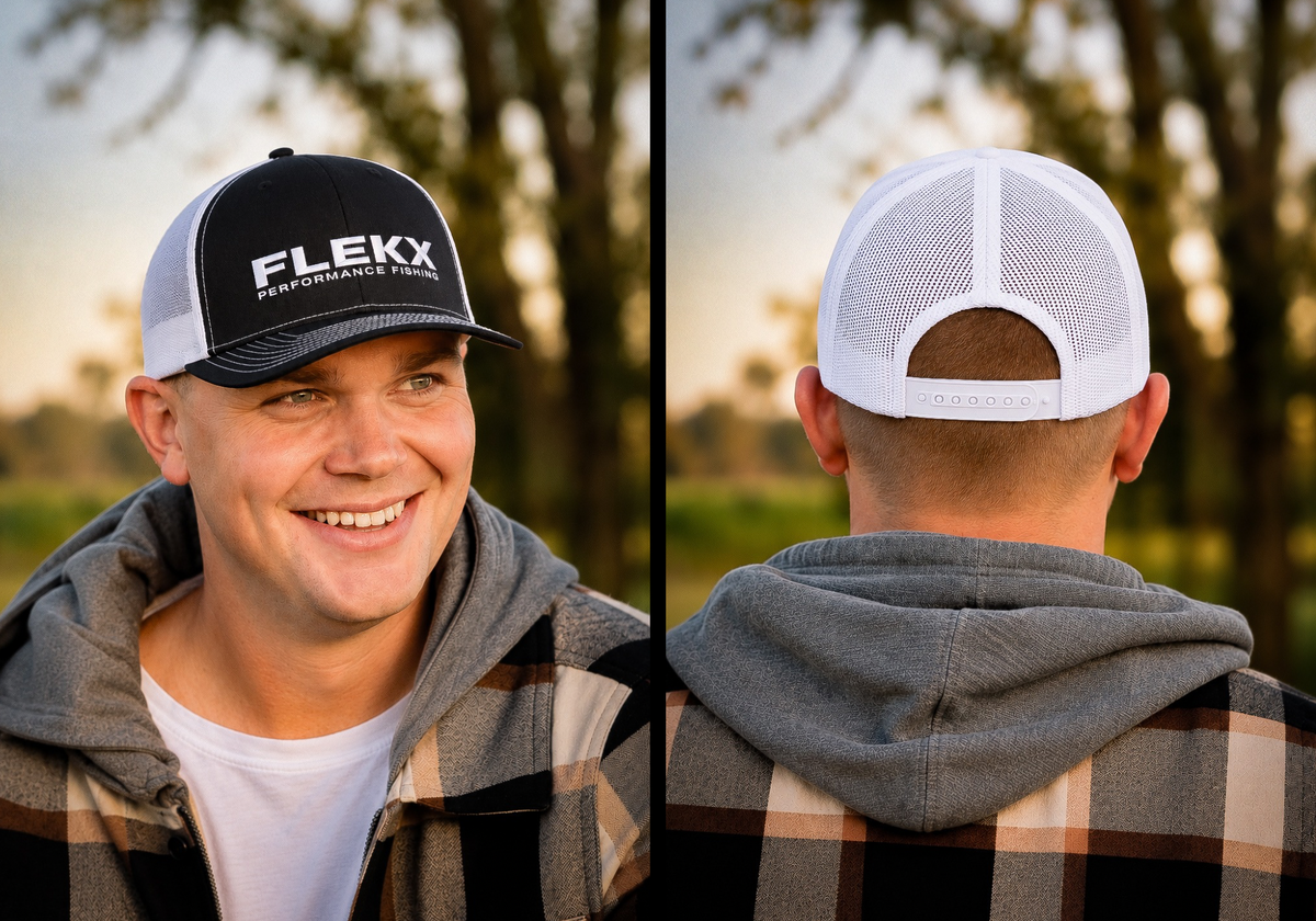 Smiling young man in a gray hoodie and plaid overshirt wearing the black-front FlekX Classic Hat at dusk; the front view shows crisp white FLEKX Performance Fishing embroidery on the structured crown, the rear view white breathable mesh with an adjustable snap closure. A christian fishing trucker hat from a veteran owned fishing apparel brand.