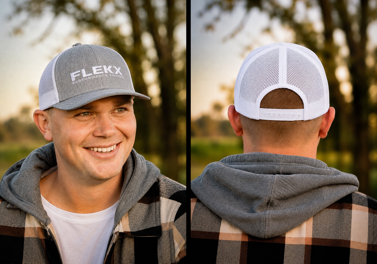 Smiling young man in a gray hoodie and plaid overshirt wearing the gray-front FlekX Classic Hat at dusk; the front view shows white FLEKX Performance Fishing embroidery on the structured crown, the rear view white breathable mesh with an adjustable snap closure. A christian fishing trucker hat - faith based fishing apparel from FlekX.